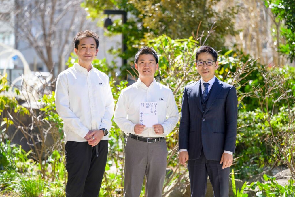 記事内に登場した3名の話者がカメラ目線でたっている。HQ藤永さんは桂川の著書である本を手に持っている