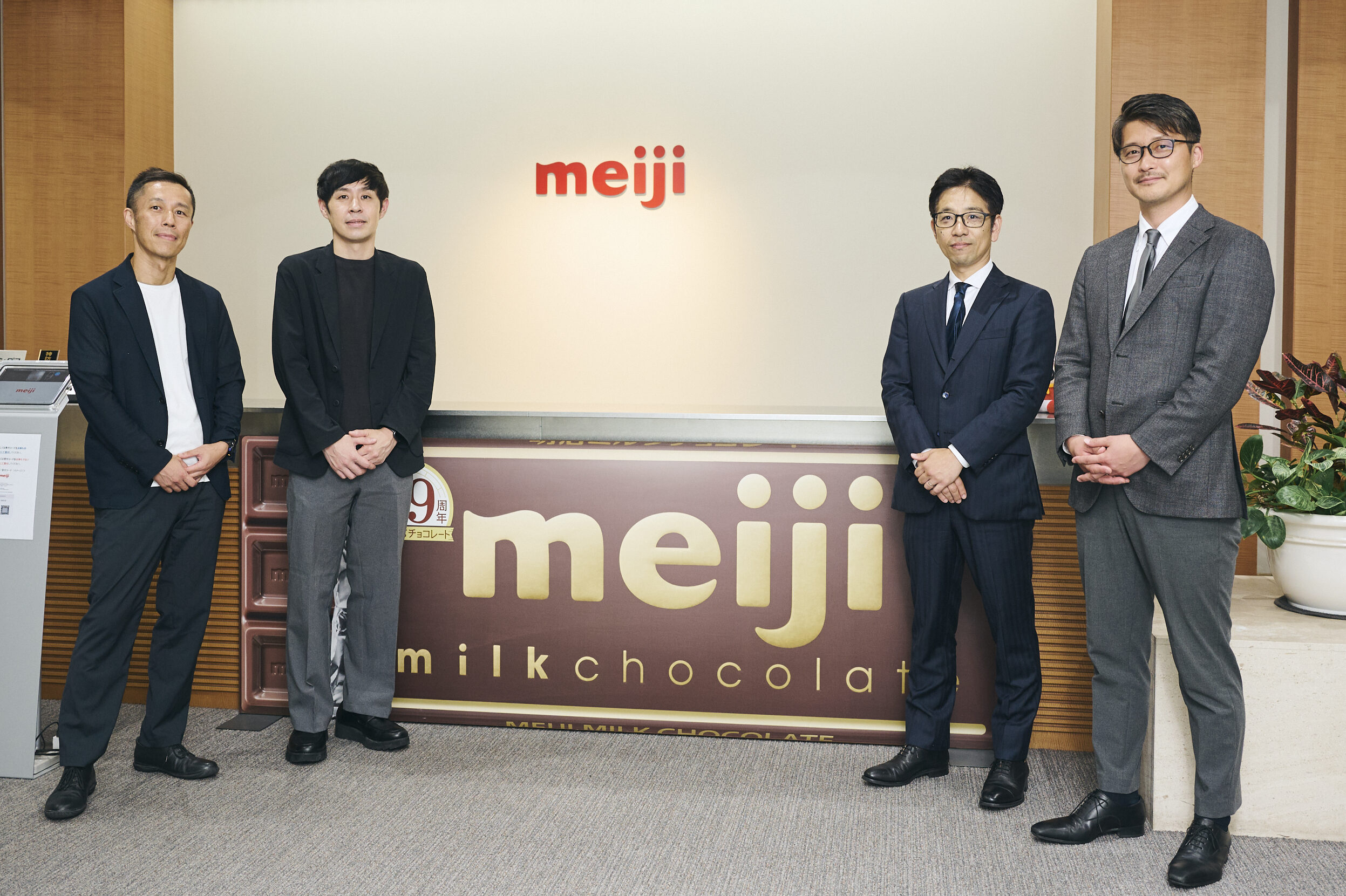 株式会社 明治様のエントランスで撮影した畑中拓一さん、吉田良さん、才流の桂川誠、犬塚啓明の4名