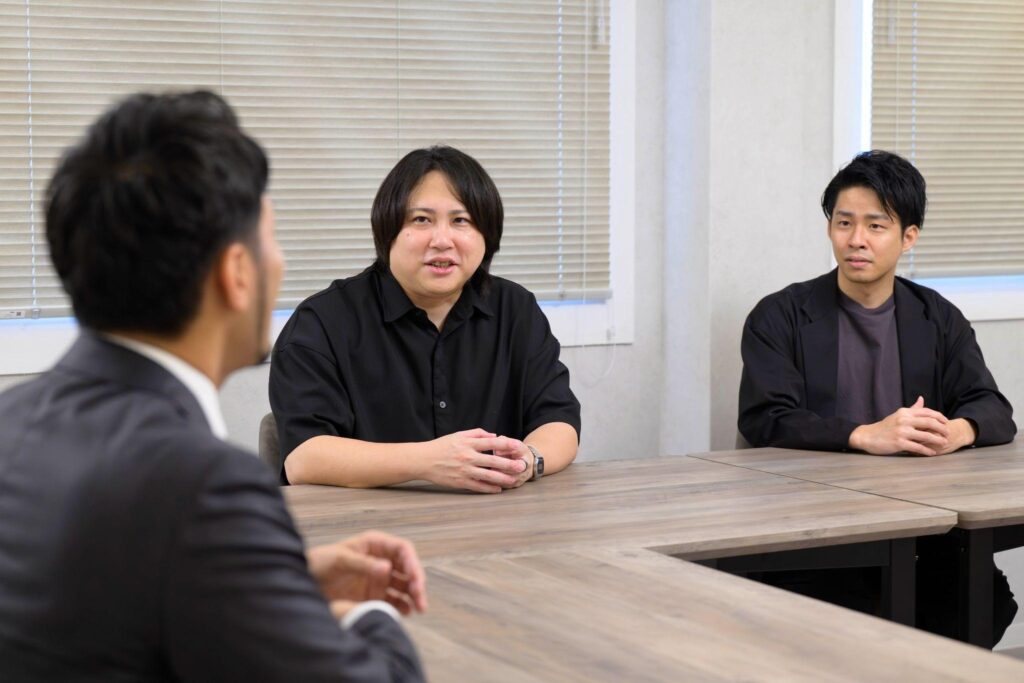 テーブルを囲んで話す横山直紀(手前)、宮本敦士さん(中央)、大羽将徳さん(右)